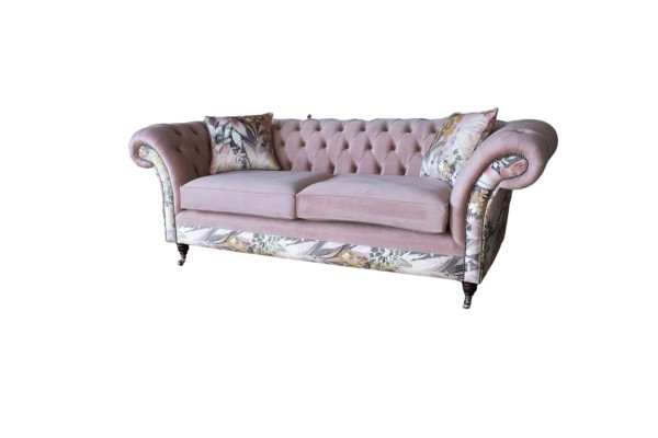 Un vivace divano Chesterfield a tre posti con delicato motivo floreale rosa.