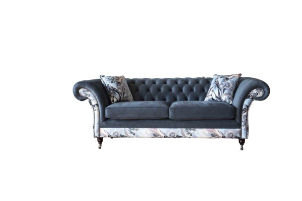 Un vistoso divano a tre posti in stile Chesterfield con delicata decorazione floreale grigia.