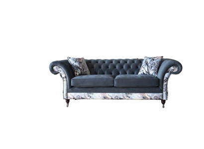 Un vistoso divano a tre posti in stile Chesterfield con delicata decorazione floreale grigia.