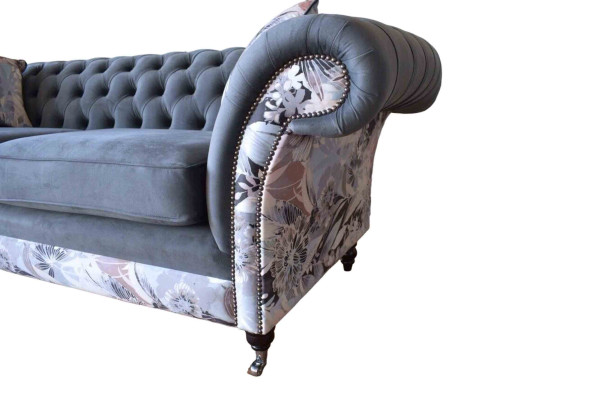 Un vistoso divano a tre posti in stile Chesterfield con delicata decorazione floreale grigia.