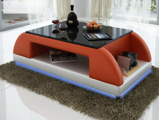 Divano moderno imbottito in pelle con tavolo da salotto in vetro.