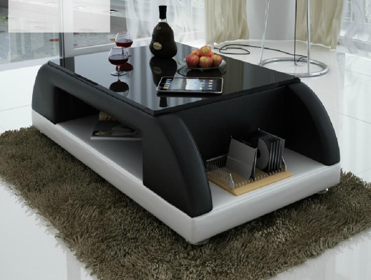 Divano moderno imbottito in pelle con tavolo da salotto in vetro.