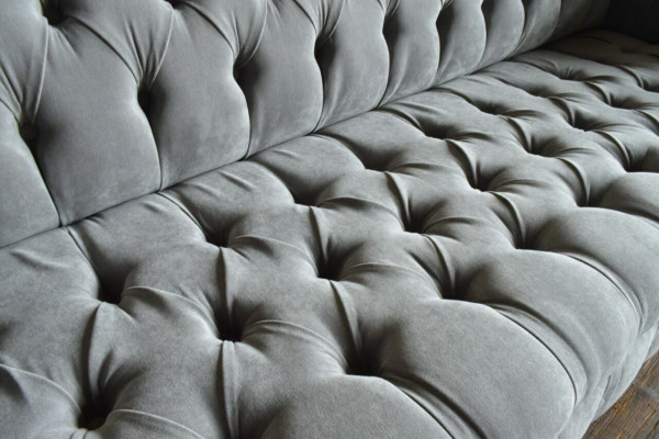 Classico divano Chesterfield 4 posti in pelle grigia, design imbottito.