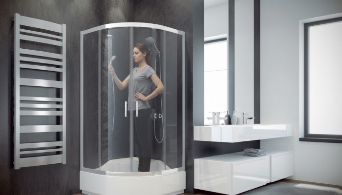 Cabina doccia angolare a quarto di cerchio con parete doccia in vetro.