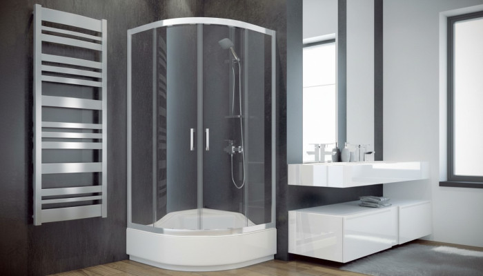 Cabina doccia angolare a quarto di cerchio con parete doccia in vetro.