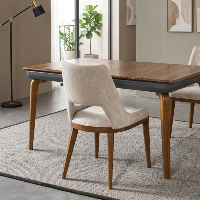 Una sedia moderna e laconica con gambe alte in legno e imbottitura di un piacevole colore crema chiaro per la sala da pranzo.