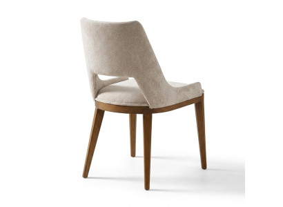 Una sedia moderna e laconica con gambe alte in legno e imbottitura di un piacevole colore crema chiaro per la sala da pranzo.