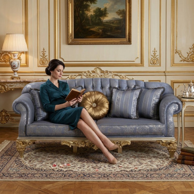 Divano classico e sofisticato in stile Chesterfield per il soggiorno con cuscini dorati.