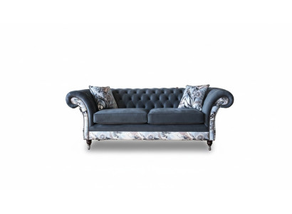 Un vistoso divano a tre posti in stile Chesterfield con delicata decorazione floreale grigia.